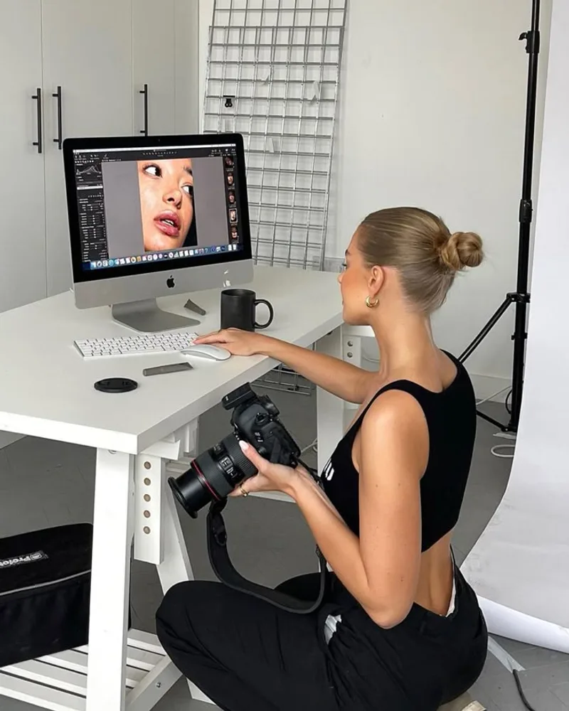 Editing photographs at a studio workstation beside a camera
