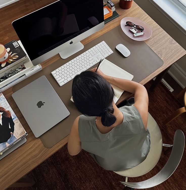 Founder working at a clean wooden desk with an iMac, laptop, notebook, and coffee