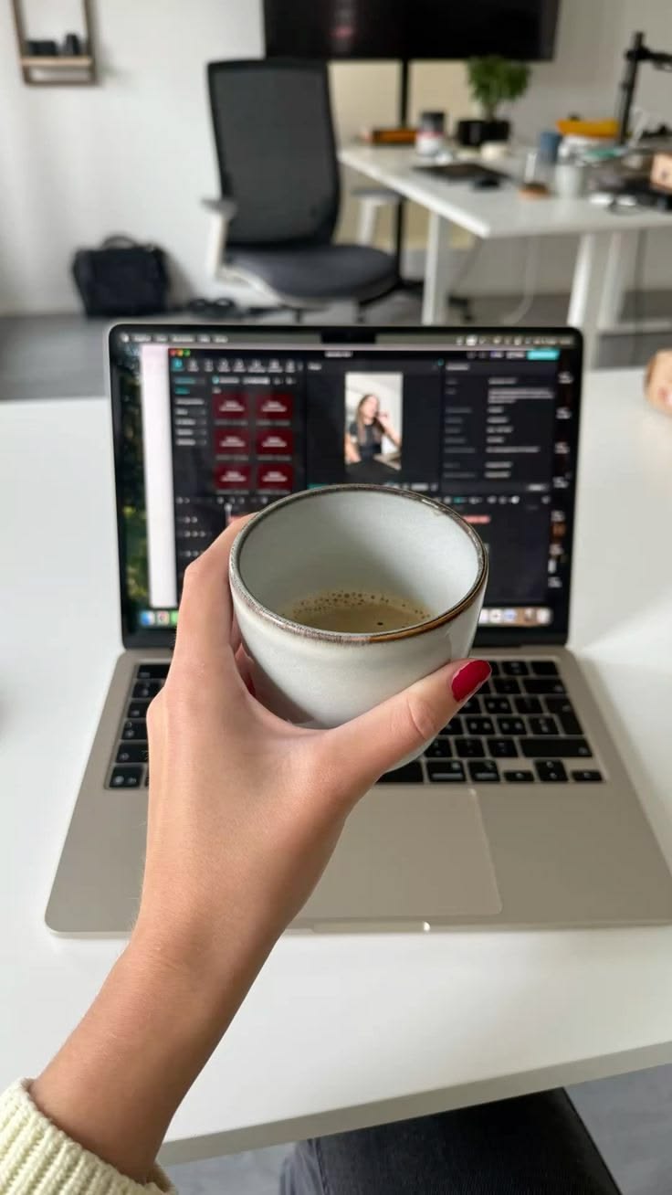 Founder holding coffee while working on offer materials at a laptop
